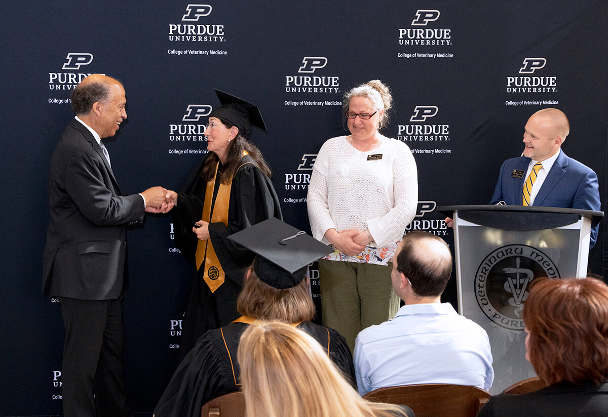 Dean of the College of Veterinary Medicine Willie Reed congratulates Brenda Green during the Veterinary Nursing Distance Learning program Pinning and Oath ceremony as Instructional Technologist Holly McCalip and Veterinary Nursing Programs Director Chad Brown look on.